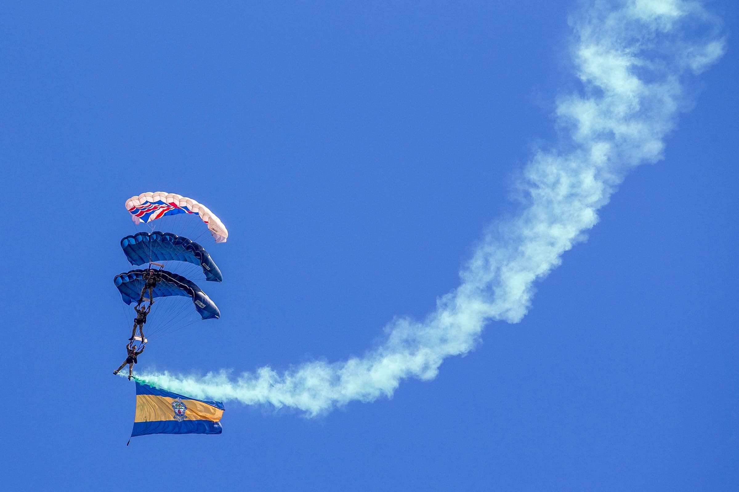 Three people parachuting in the sky at the English Riviera Festival 