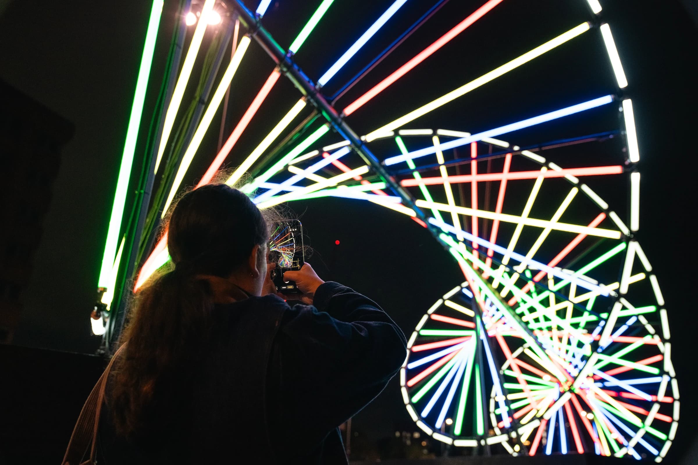 Girl taking photo of like sculpture at night